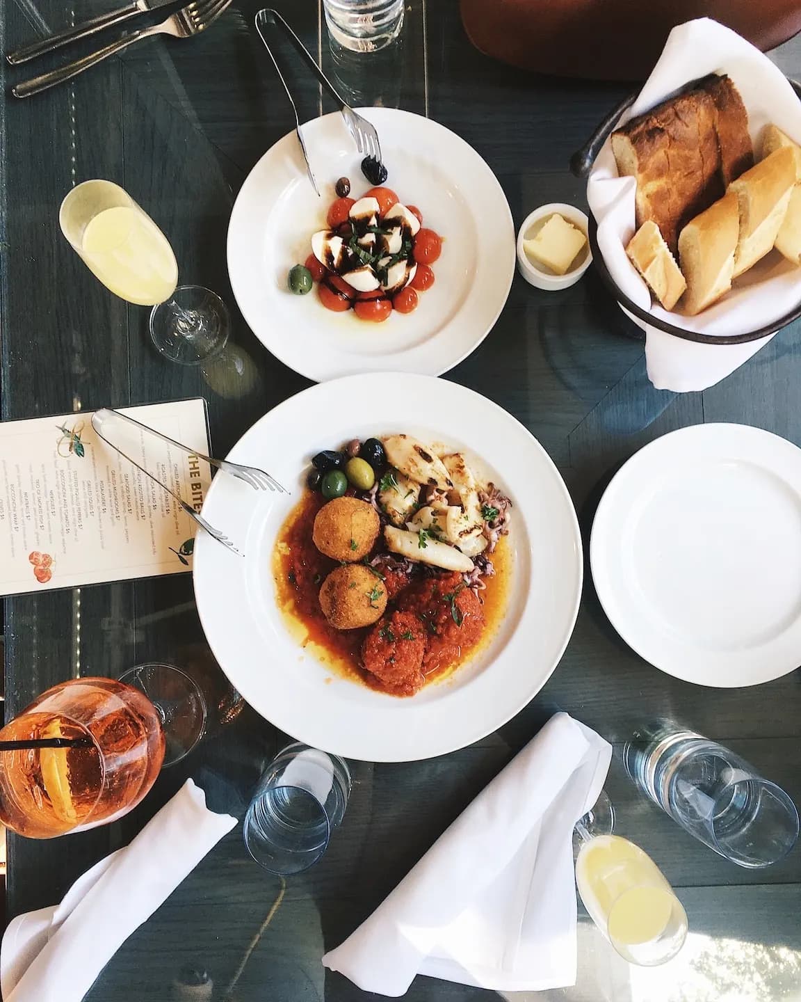 Une table dressée vue du dessus : assiettes, pain, verres et couverts en plein service