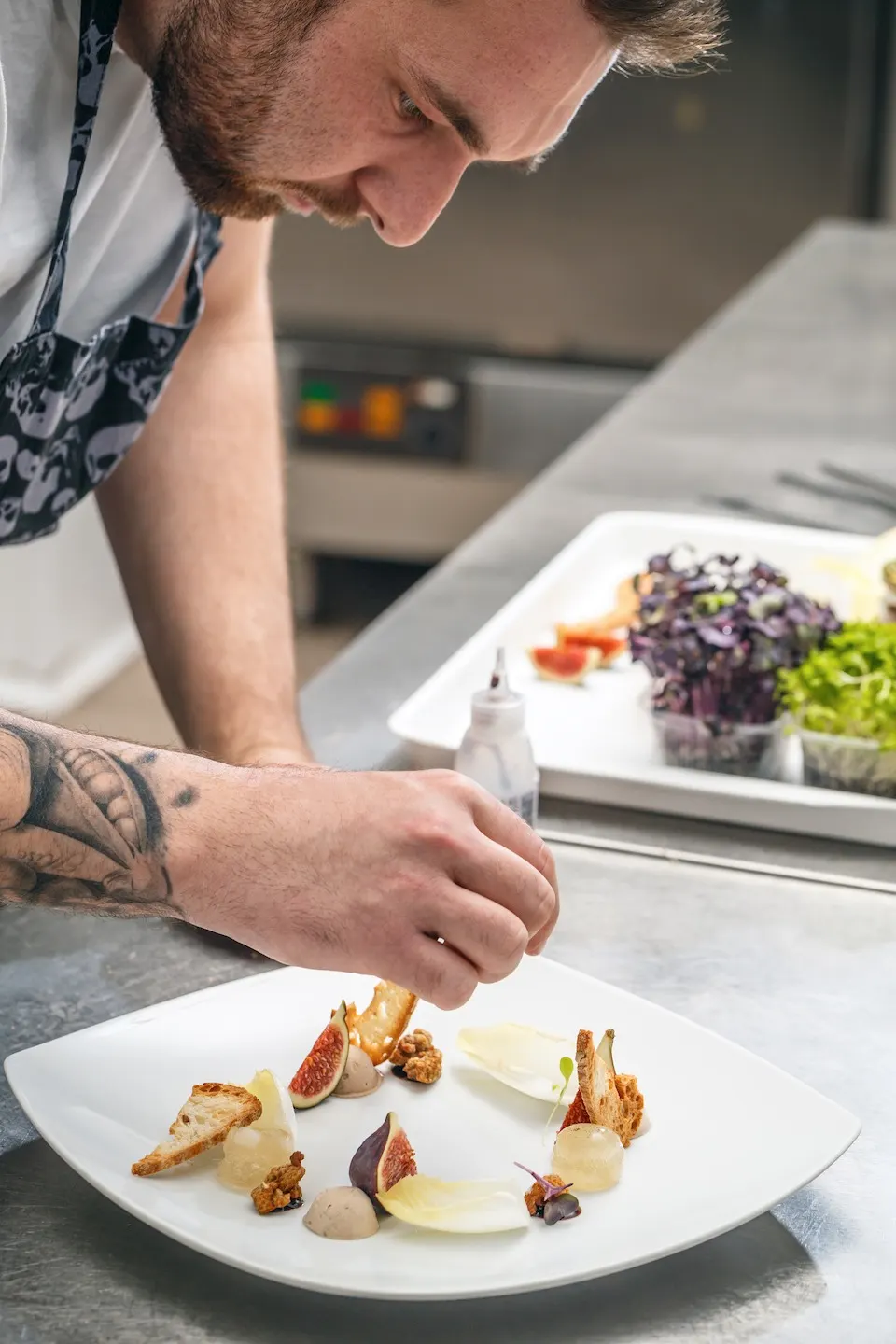 Un cuisinier penché sur une assiette, en train de disposer les derniers éléments